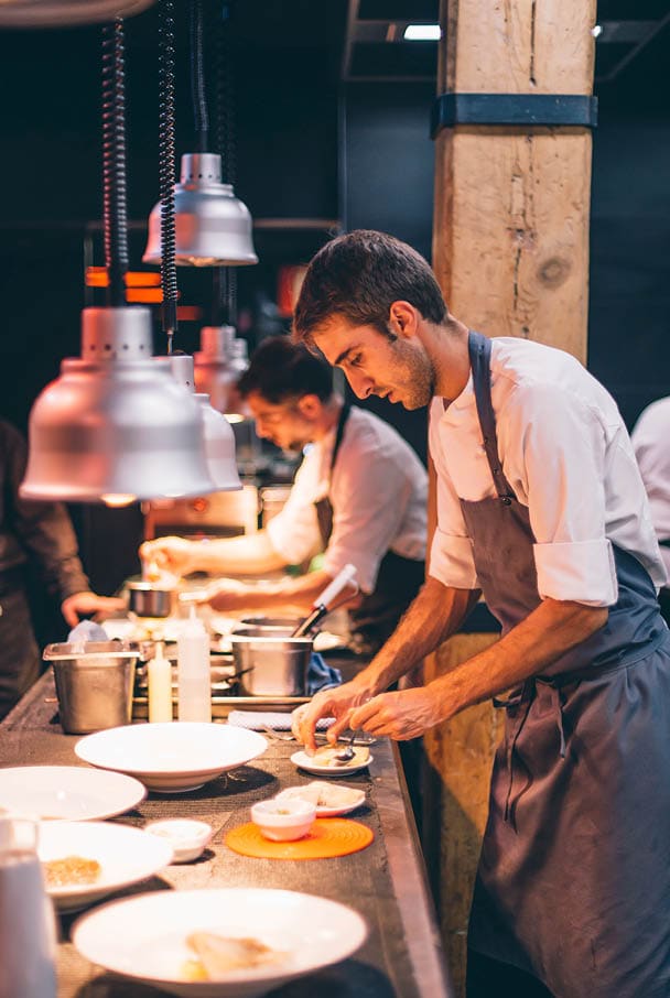 Chef serving food on plates in the kitchen of a restaurant