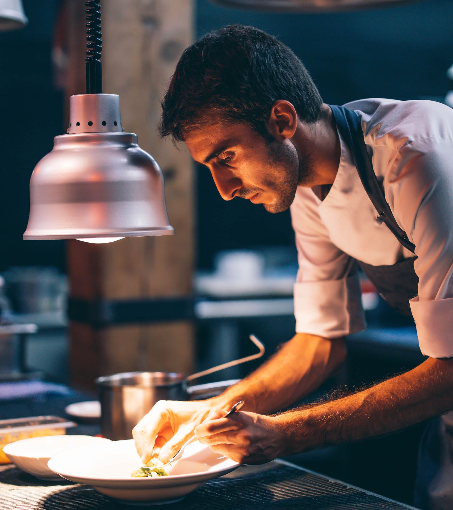 Cook serving food on a plate in the kitchen of a restaurant
