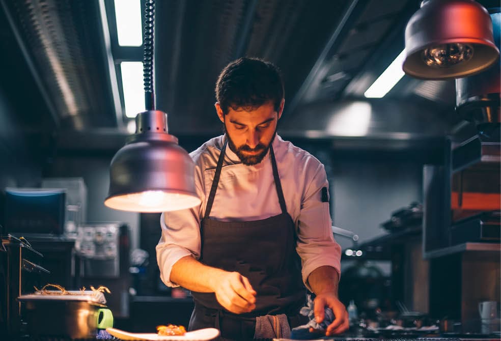 Chef serving food on plates in the kitchen of a restaurant