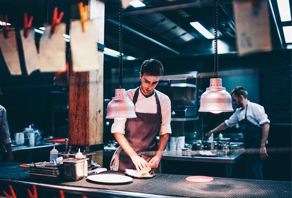 Cook serving food on a plate in the kitchen of a restaurant