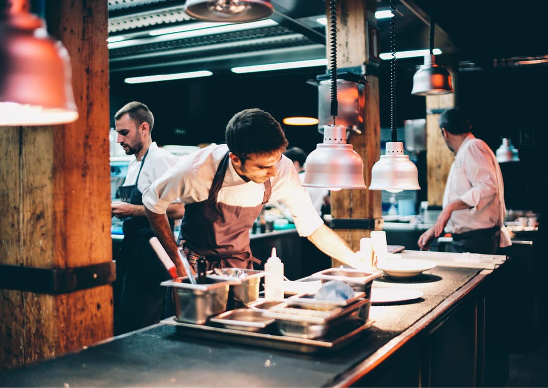 Cook serving food on a plate in the kitchen of a restaurant