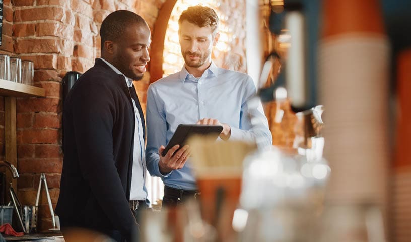 Multicultural Coffee Shop Owners Meeting Behind the Counter and Working on Tablet Computer and Checking Inventory in a Cozy Loft-Style Cafe. Successful Restaurant Managers and Barista at Work.; Shutterstock ID 1882428628; purchase_order: -; job: -; client: -; other: -